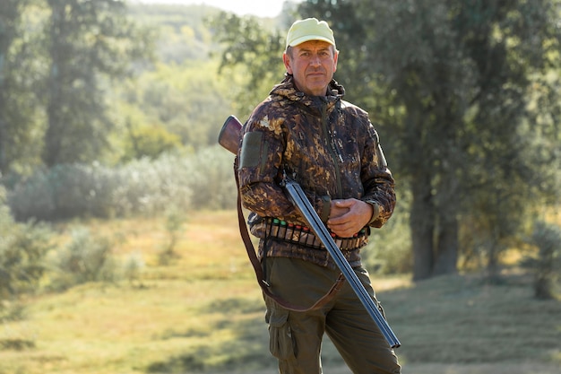 Hombre cazador en camuflaje con una pistola durante la caza en busca de aves silvestres o caza