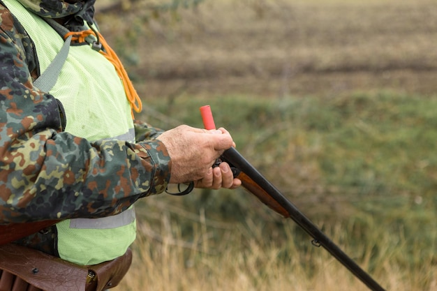 Hombre cazador en camuflaje con una pistola durante la caza en busca de aves silvestres o caza