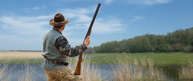 Foto hombre cazador en camuflaje con una pistola durante la caza en busca de aves silvestres o caza