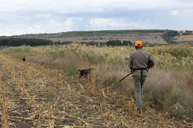 Hombre cazador en camuflaje con una pistola durante la caza en busca de aves silvestres o caza