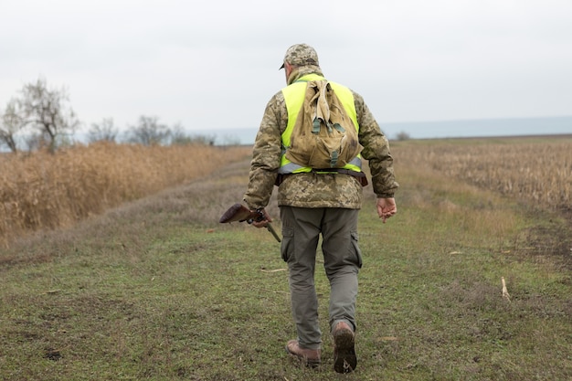 Hombre cazador en camuflaje con una pistola durante la caza en busca de aves silvestres o caza