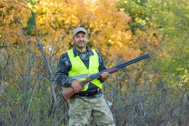 Foto hombre cazador en camuflaje con una pistola durante la caza en busca de aves silvestres o caza