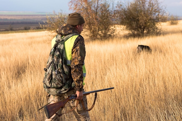 Hombre cazador en camuflaje con una pistola durante la caza en busca de aves silvestres o caza