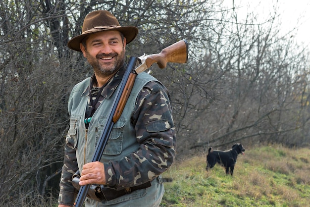 Foto hombre cazador en camuflaje con una pistola durante la caza en busca de aves silvestres o caza