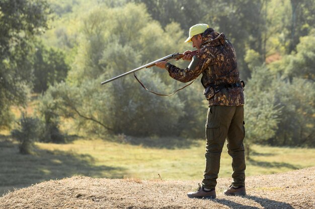 Hombre cazador en camuflaje con una pistola durante la caza en busca de aves silvestres o caza.