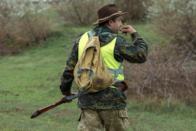 Hombre cazador en camuflaje con una pistola durante la caza en busca de aves silvestres o caza.