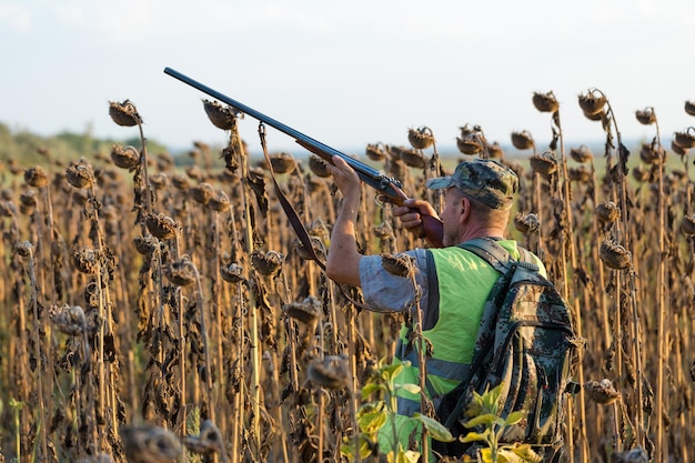 Hombre cazador en camuflaje con una pistola durante la caza en busca de aves silvestres o caza.