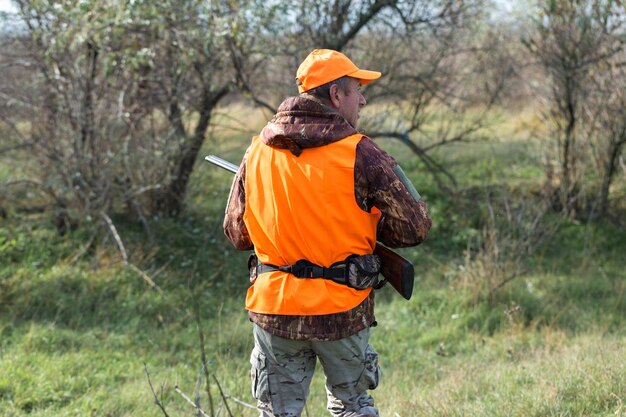 Hombre cazador en camuflaje con una pistola durante la caza en busca de aves silvestres o caza