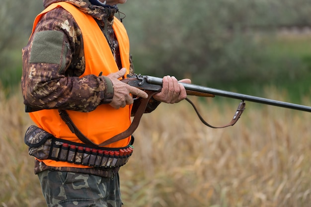 Hombre cazador en camuflaje con una pistola durante la caza en busca de aves silvestres