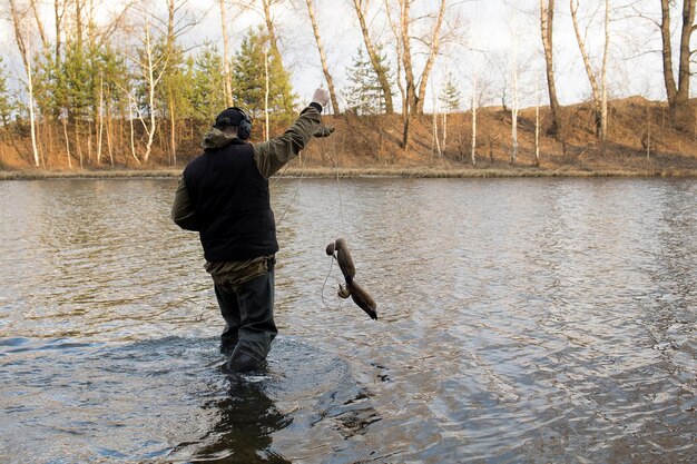 Hombre cazador caza con un arma de patos en la orilla del río