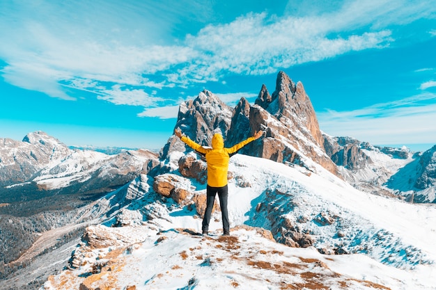 Hombre celebrando el éxito en la cima de la montaña nevada