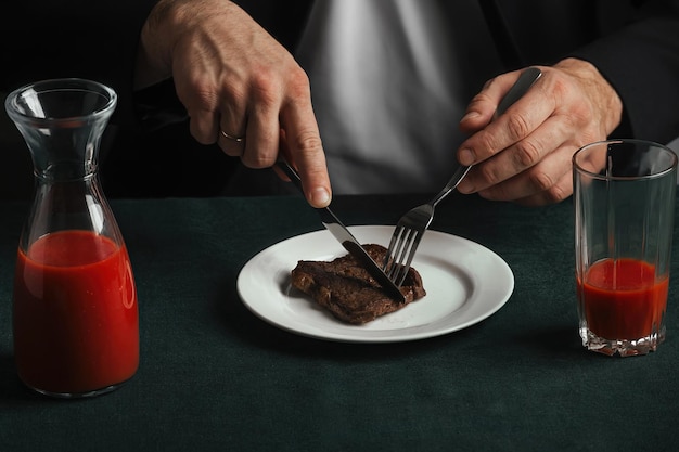 hombre en la cena que consiste en un delicioso filete de ternera a la parrilla y jugo de tomate rojo brillante