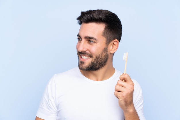 Hombre con cepillo de dientes sobre pared azul aislado