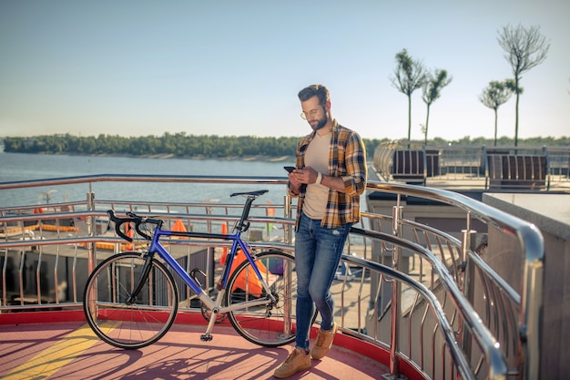 Hombre cerca de bicicleta con smartphone en sus manos