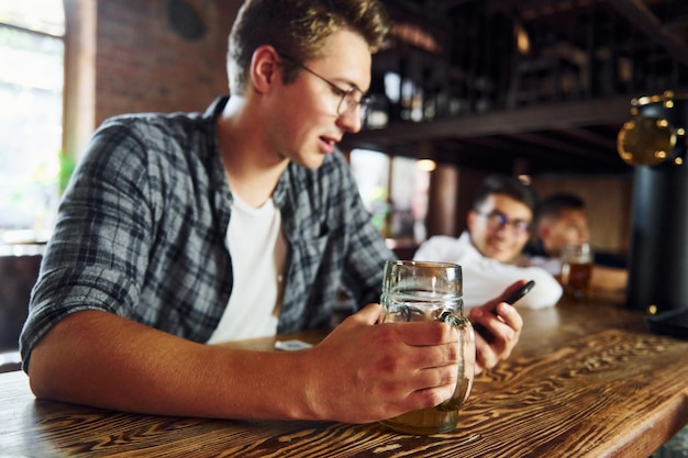 Hombre con cerveza en ropa casual sentado en el pub