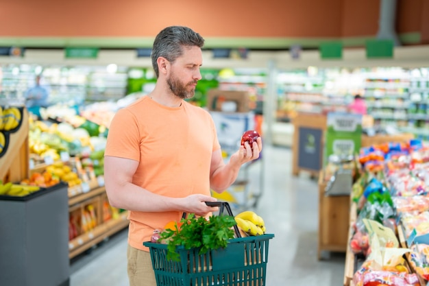 Hombre con cesta de la compra comprando en el supermercado Cesta de la compra de la tienda de comestibles Pancarta con el hombre para la tienda de comestibles o el supermercado Hombre eligiendo comida en la tienda o en la tienda de comestibles