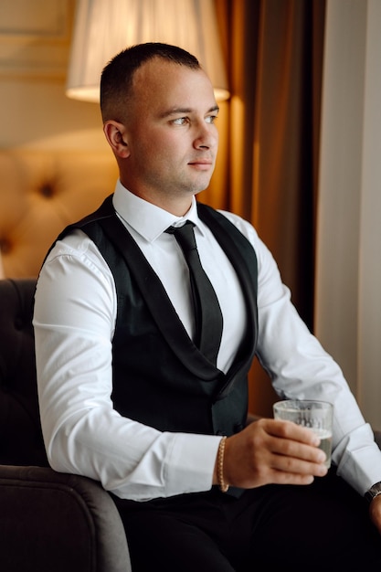 Foto un hombre con un chaleco y corbata está bebiendo un vaso de cerveza