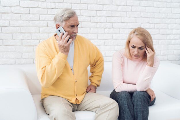 Un hombre con una chaqueta amarilla está hablando por su teléfono inteligente.