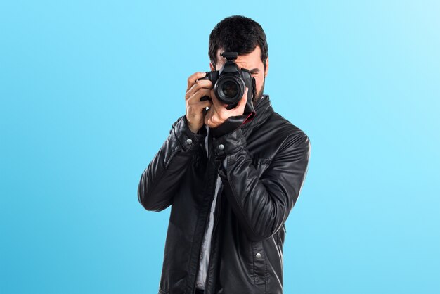 Hombre con chaqueta de cuero fotografiando sobre fondo de colores