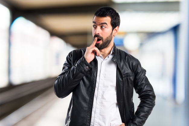 Hombre con chaqueta de cuero haciendo gesto sorpresa sobre fondo desenfocado