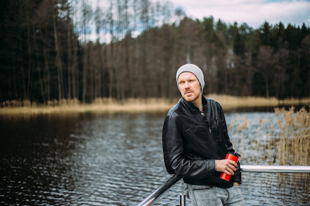 Hombre con chaqueta de cuero junto al lago