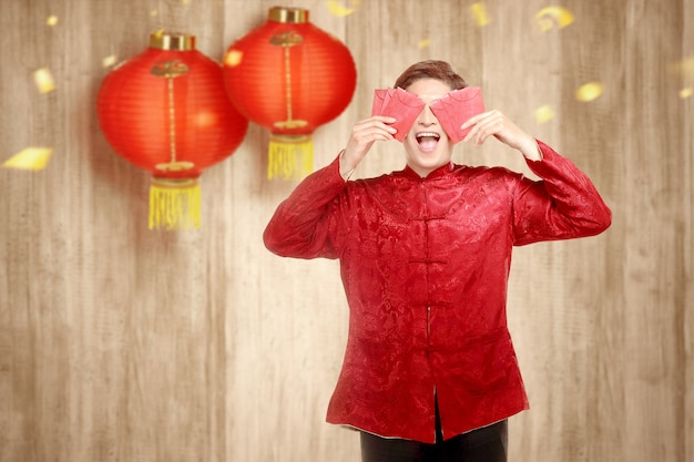 Un hombre chino asiático en un vestido cheongsam con sobres rojos