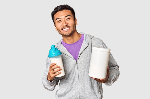 Hombre chino en forma con batido de proteínas y botella en el estudio