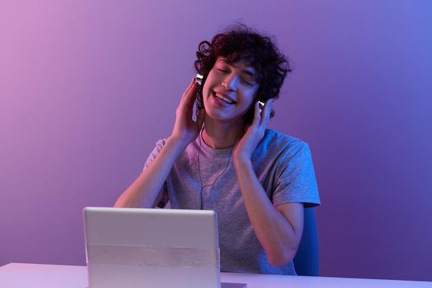 Hombre ciberespacio jugando con auriculares frente a un fondo violeta portátil Foto de alta calidad