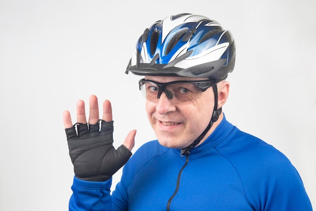 Hombre ciclista con casco de bicicleta y gafas transparentes sobre un fondo claro