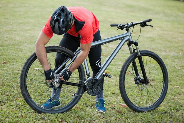 Hombre ciclista de montaña arreglando su cadena de bicicleta