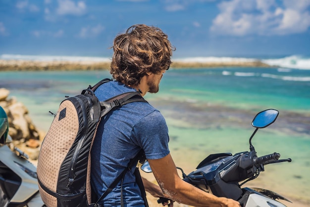 Un hombre en un ciclomotor, moto admira el hermoso mar