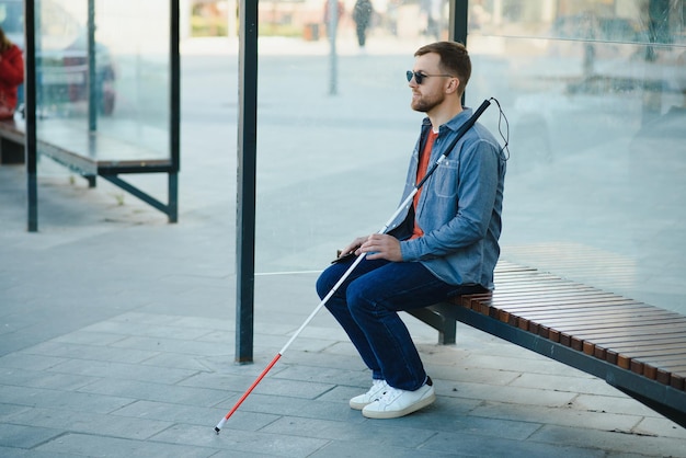 Hombre ciego esperando el autobús en una estación de autobuses