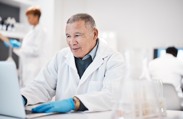 Foto hombre científico y escribiendo en una computadora portátil en la investigación médica de laboratorio con un médico de doctorado senior e ingresando los resultados del experimento en línea innovación científica masculina en biología y registro digital de prueba científica