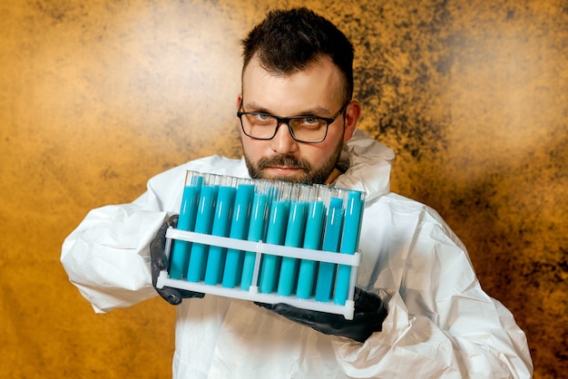 Un hombre científico en un traje protector con frascos en sus manos con una vacuna azul