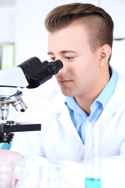 Hombre científico utilizando microscopio en laboratorio