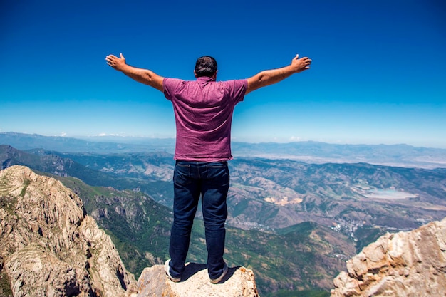 Hombre en la cima de la montaña Diseño conceptual manos en alto