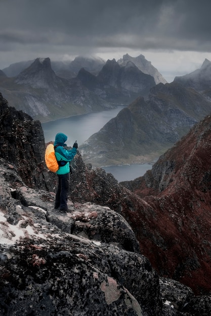 un hombre se para en la cima de la montaña y toma una foto en su teléfono móvil