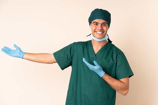 Hombre cirujano en uniforme azul sobre la pared extendiendo las manos a un lado para invitar a venir