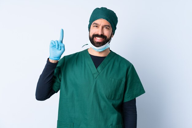 Hombre cirujano en uniforme verde sobre pared aislada apuntando una gran idea