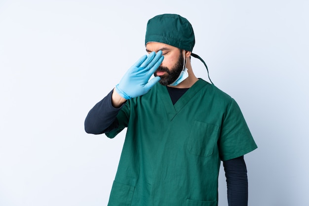 Hombre cirujano en uniforme verde sobre pared aislada haciendo gesto de parada y decepcionado