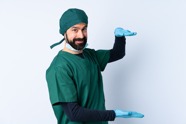 Hombre cirujano en uniforme verde sobre pared con espacio en blanco