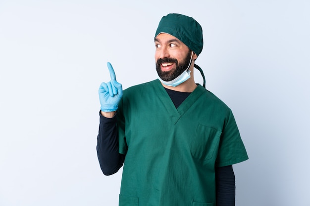 Hombre cirujano en uniforme verde sobre la pared con la intención de darse cuenta de la solución mientras levanta un dedo