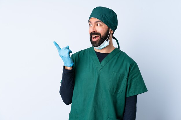 Hombre cirujano en uniforme verde sobre la pared con la intención de darse cuenta de la solución mientras levanta un dedo