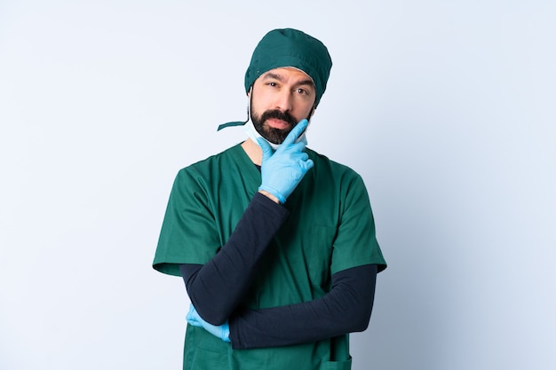 Hombre cirujano en uniforme verde sobre pensamiento de pared