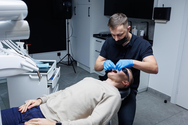 Un hombre en una cita con un ortodoncista tratamiento de ortodoncia de los dientes Oficina de ortodoncia médica moderna Cuidado dental