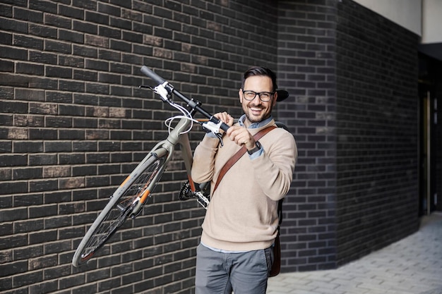 Un hombre de la ciudad lleva una bicicleta al hombro.