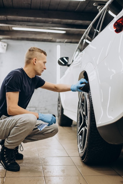 Hombre en coche limpiando neumáticos de pulido