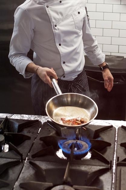 Un hombre cocina freidoras en un fuego de cocina