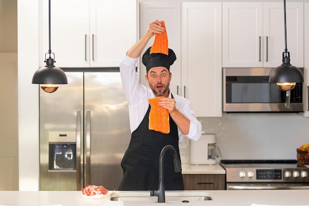 Hombre en la cocina moderna preparando comida saludable pescado salmón hombre guapo está cocinando salmón pescado fresco