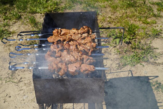 Hombre cocinando carne de cordero shashlik marinada a la parrilla en sesgo de metal